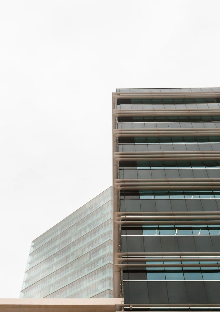 Modern glass-and-steel commercial office building façade — Eurobarómetro 1 June 2026 prints Portugal third in the EU on SME recruiting difficulty at 35%