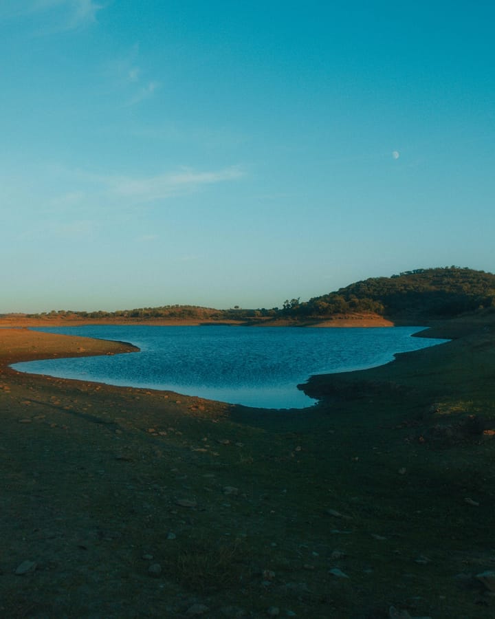 An Alentejo-style reservoir at dusk with a moon overhead — illustrative of Portugal's mid-2026 water-storage read