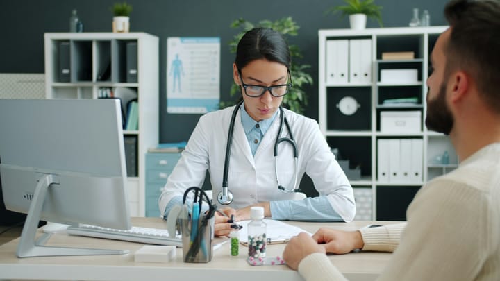Doctor with a stethoscope consulting a patient at a desk