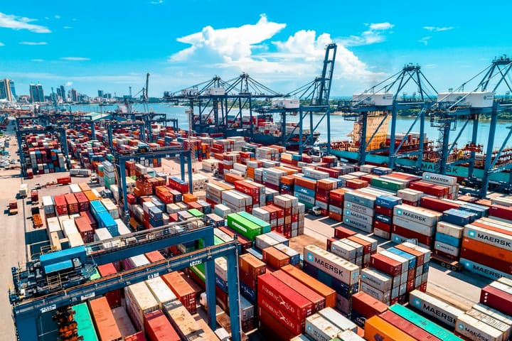 Aerial view of stacked shipping containers and gantry cranes at an industrial container port — illustrative of the Sines port and ZILS expansion.
