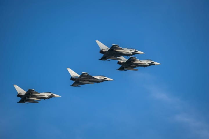 A formation of four Eurofighter Typhoon military fighter jets flying together against a clear blue sky.