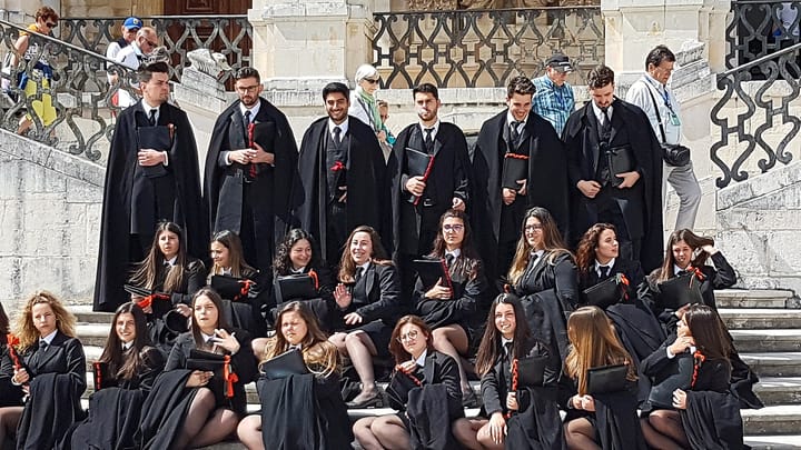 University of Coimbra students in traditional black academic robes on campus steps