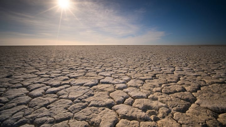 The sun blazing over a vast expanse of cracked, sun-baked earth