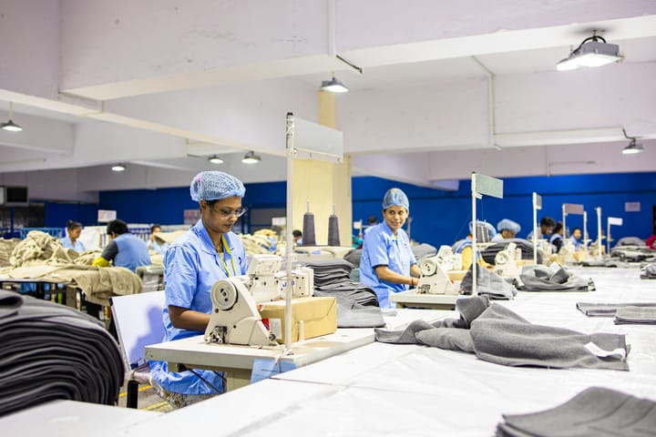 Workers at sewing machines on the floor of a garment factory