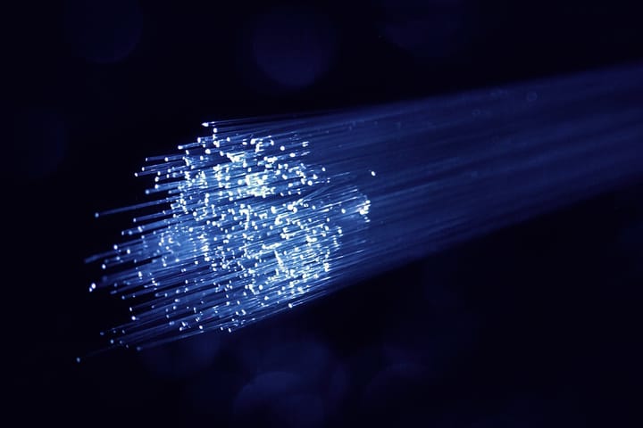 Illuminated blue fibre-optic strands fanning out against a dark background