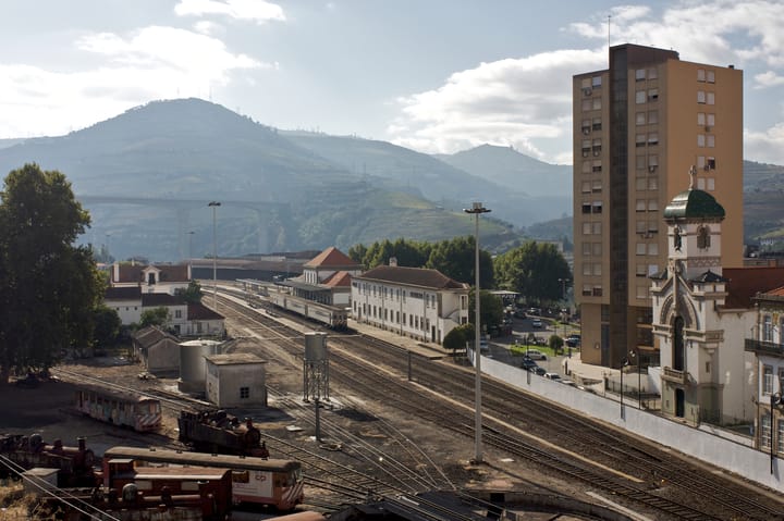 The railway station at Peso da Regua, Portugal, with tracks, trains and the terraced Douro hills behind