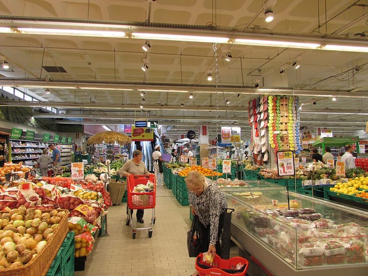 The fresh-produce aisle inside a Continente supermarket in Portugal, with shoppers and euro price tags