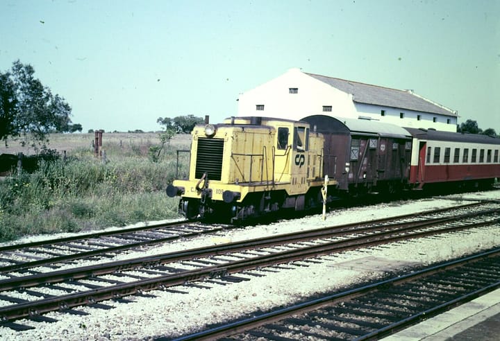 A yellow Comboios de Portugal locomotive and carriages at a rural station on the Linha do Alentejo in southern Portugal