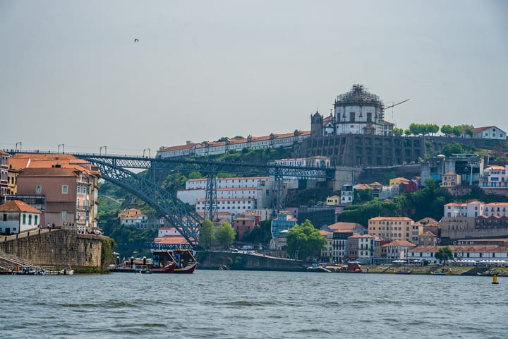The Douro river between Porto and Vila Nova de Gaia, with the double-deck Dom Luis I bridge, riverside houses, the Serra do Pilar monastery on the hill and boats on the water