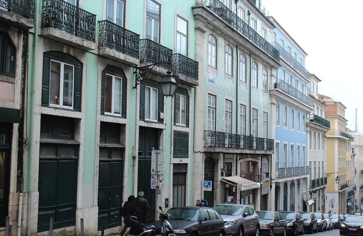 A row of traditional townhouses with wrought-iron balconies and tiled facades on Rua da Madalena in Lisbon