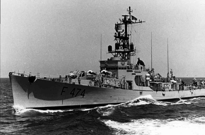 A Portuguese Navy frigate marked F 474 sailing at speed through open sea, viewed from the front left