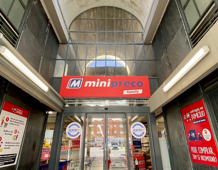 The red Minipreço supermarket entrance sign inside a building in Lisbon, Portugal, above automatic glass doors