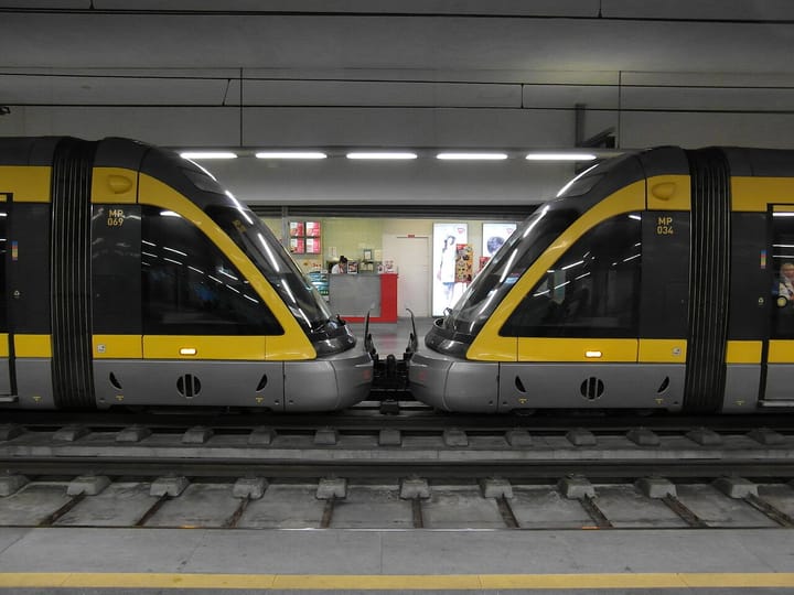 Two yellow-and-black Metro do Porto light-rail trams parked nose to nose at an underground station platform in Porto