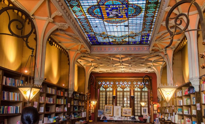 The ornate interior of the Lello bookstore in Porto, with carved wooden shelves, hanging lamps and a stained-glass ceiling