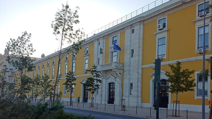 The yellow façade of the Ministry of Finance headquarters in Lisbon, flying the Portuguese and EU flags, seat of Portugal's tax authority
