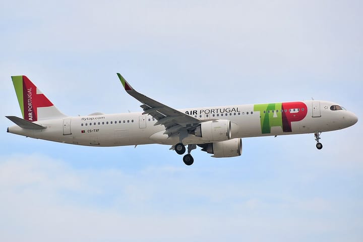 A TAP Air Portugal Airbus A321neo in flight with landing gear down, showing the airline's red, green and white livery