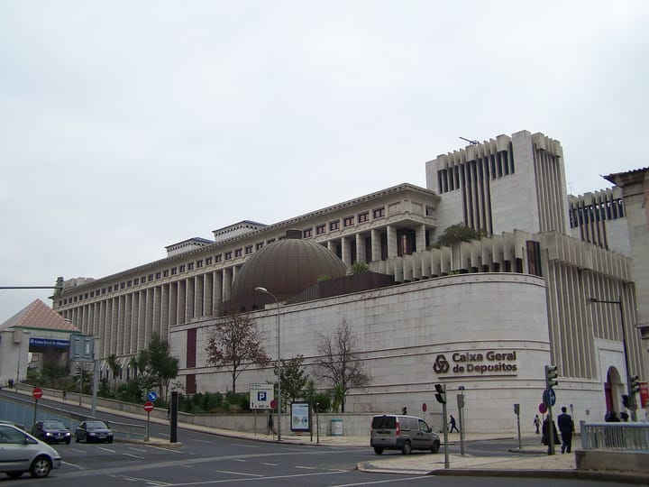 The headquarters of Caixa Geral de Depósitos in Lisbon, a large pale-stone bank building with the Caixa Geral de Depósitos name and logo on its curved outer wall