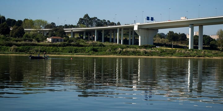 The Ponte do Freixo motorway viaduct carrying Porto's ring road high over the River Douro, with a lorry crossing and a small boat on the water below