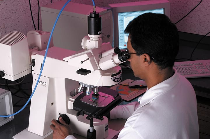 A researcher examines a sample under a microscope in a biomedical laboratory