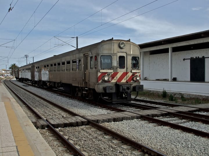 An older silver CP diesel regional train with red chevrons standing at the platform of Faro railway station in the Algarve
