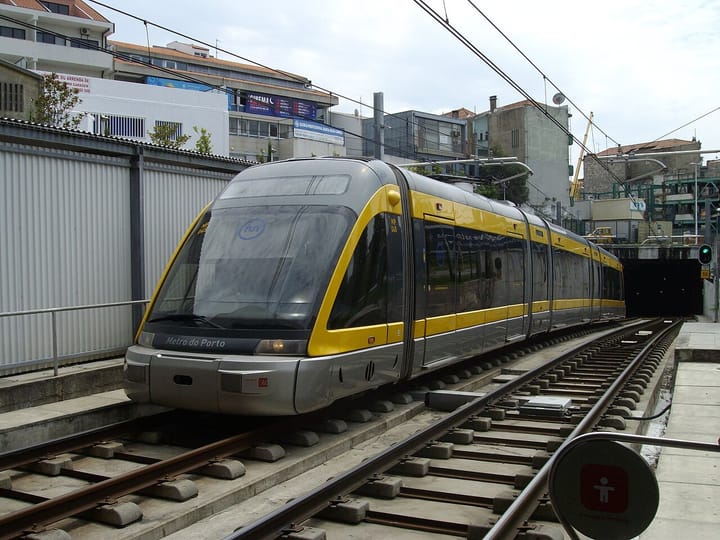 A yellow and silver Metro do Porto light-rail train at a station platform in Porto