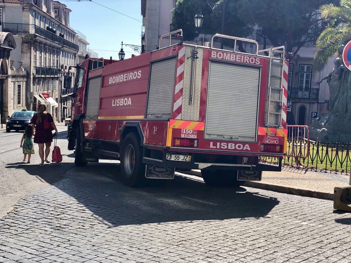 A red Bombeiros Lisboa fire engine on a cobbled Lisbon street