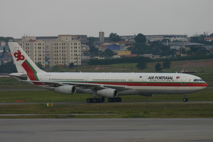 A TAP Air Portugal Airbus A340 airliner in red-and-green livery on an airport runway