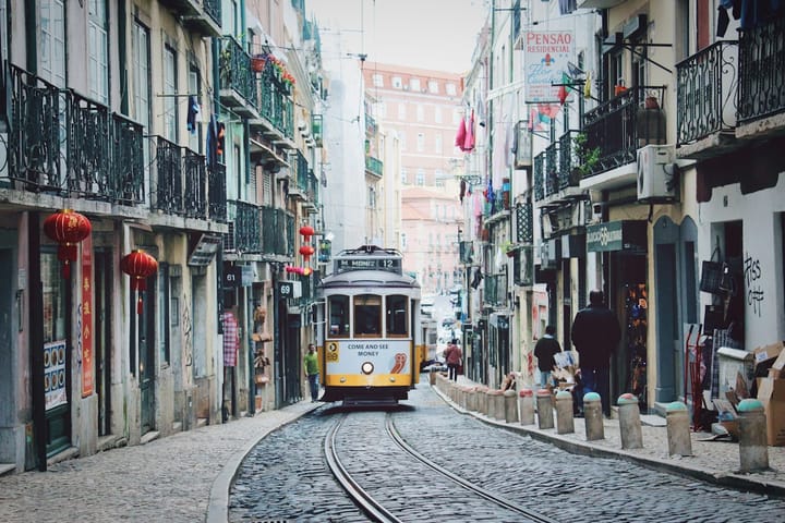 A yellow Carris tram climbing a cobbled street in central Lisbon