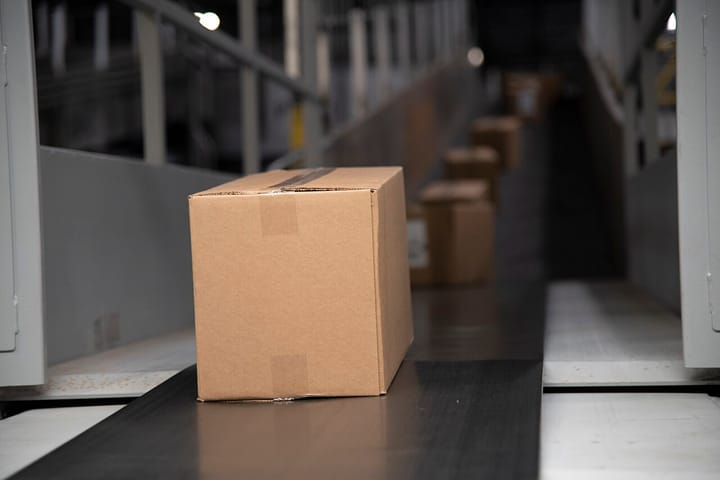 Plain cardboard parcels moving along a conveyor belt inside a package distribution centre