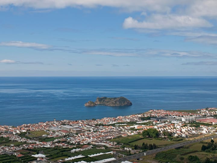 An aerial view of Vila Franca do Campo on Sao Miguel in the Azores, its white houses spread along the coast with the Vila Franca islet offshore