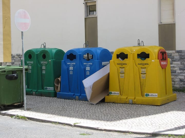 Green, blue and yellow recycling containers (ecopontos) for glass, paper and plastic-and-metal standing on a Portuguese street