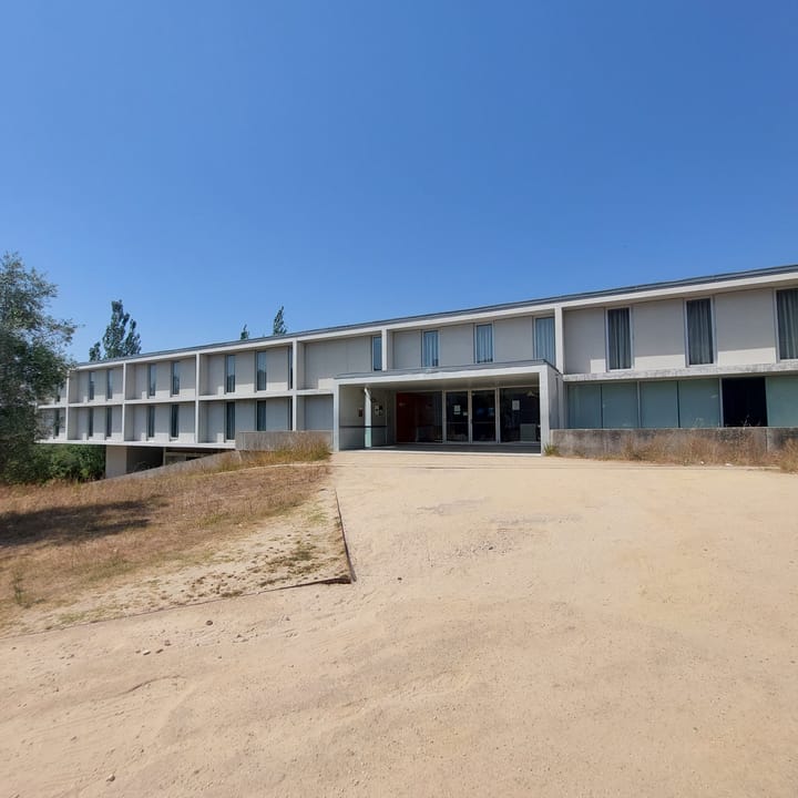 The modern white facade of the University of Coimbra Polo III student residence hall under a clear blue sky