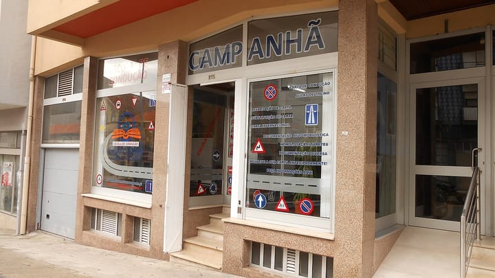 The window of a Portuguese driving school in Porto, displaying road-sign decals and carta de condução services