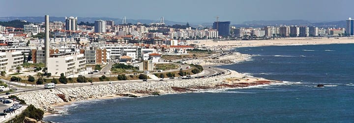 An aerial view of Figueira da Foz on the Portuguese Atlantic coast, with white apartment blocks, a long sandy beach and the coastal road curving along the shore
