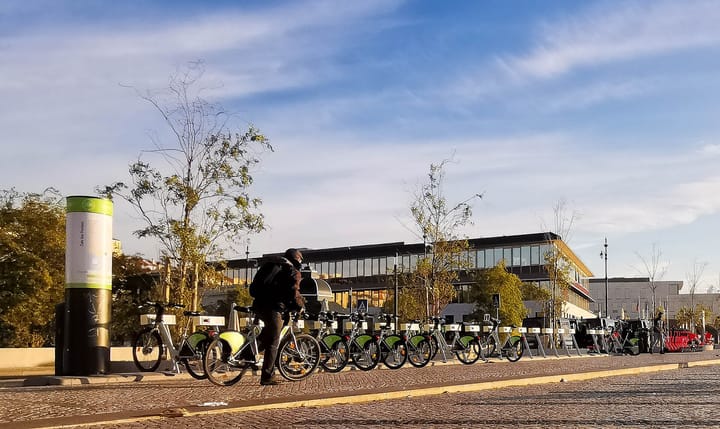 A row of green Gira shared bikes docked at a station in Lisbon's Cais do Sodré, part of the EMEL bike-share network