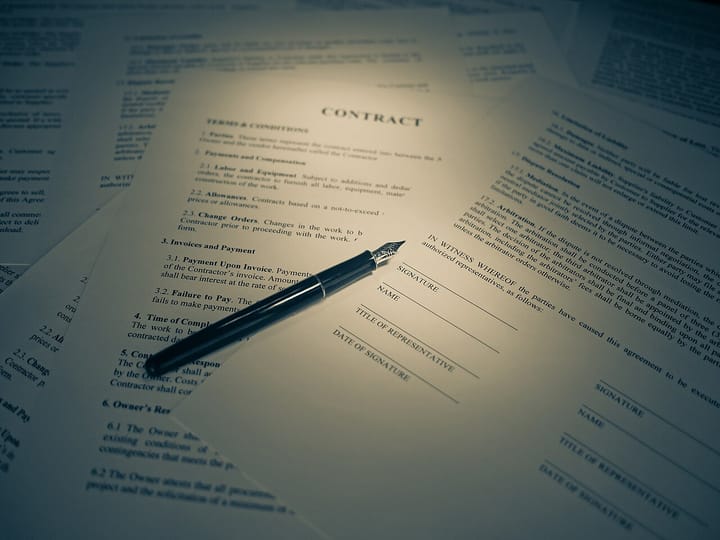 A printed contract headed CONTRACT with a black fountain pen resting across the signature, name and date-of-signature lines