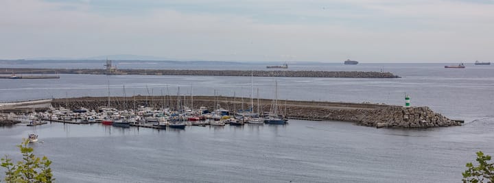 Marina and breakwater at Sines, Portugal, with commercial cargo ships on the horizon out at sea
