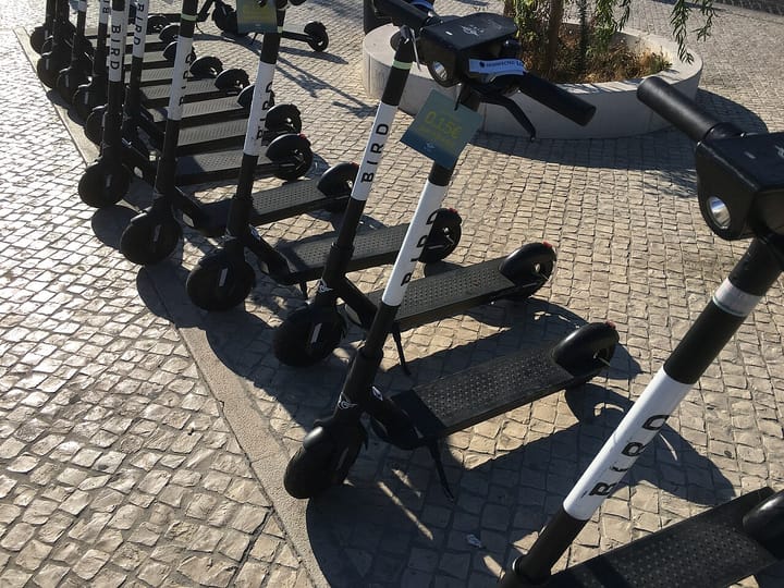 A row of shared electric scooters parked on Portuguese calcada paving in Lisbon