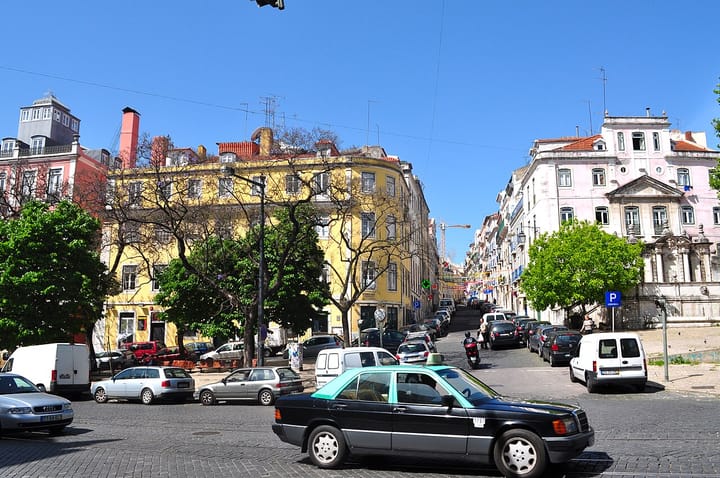 A traditional black-and-green Lisbon taxi in a city square