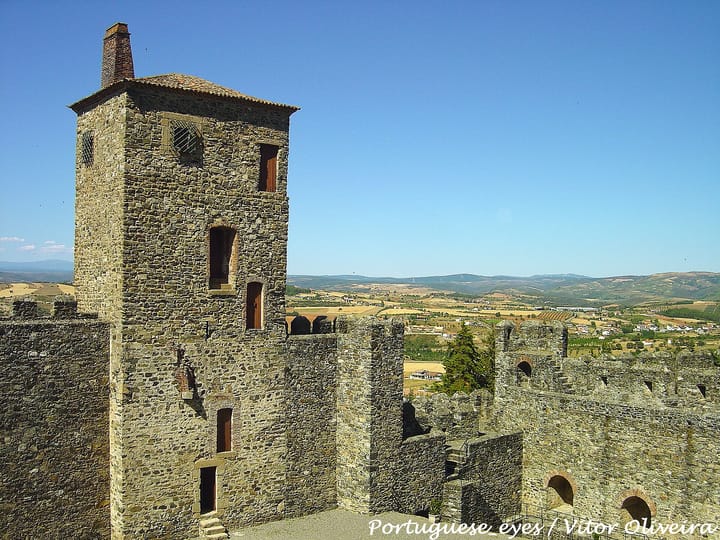 The stone keep and battlements of Bragança castle in Trás-os-Montes, with the hills, fields and scattered villages of the northern interior stretching away behind it.