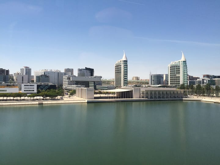 The glass office and residential towers of Parque das Nacoes, Lisbon's modern business district, seen across the waterfront under a clear blue sky