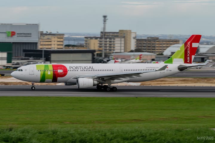 A TAP Air Portugal Airbus A330 in the airline's green and red livery on the runway at Lisbon airport, with the TAP Maintenance hangar behind it