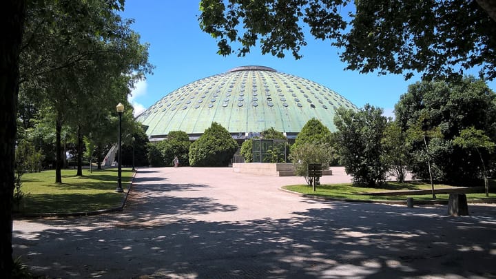 The green domed roof of the Pavilhao Rosa Mota seen from a tree-lined path in the Palacio de Cristal gardens in Porto