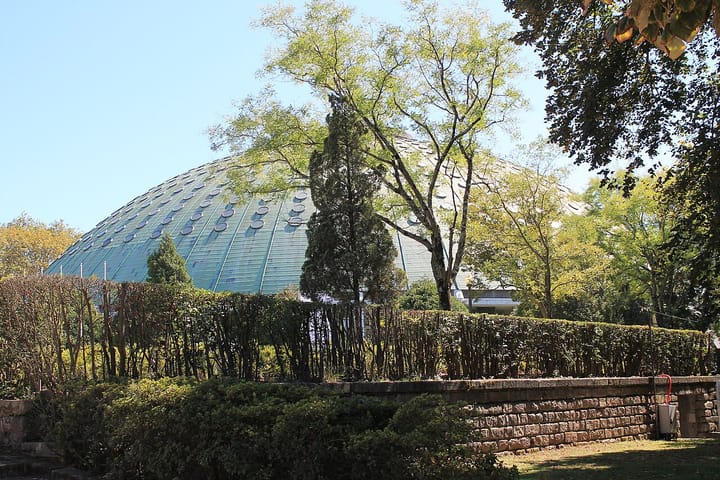 The green dome of the Rosa Mota pavilion rising above clipped hedges and trees in the gardens of the Palácio de Cristal in Porto, where the city's Book Fair is held