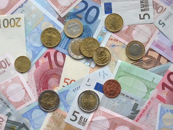 A spread of euro banknotes and assorted euro coins representing money and savings