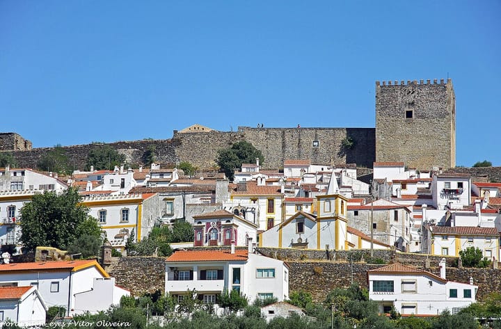 The whitewashed, red-roofed houses of Castelo de Vide climbing the hillside below the castle keep in the Alto Alentejo, under a cloudless blue sky
