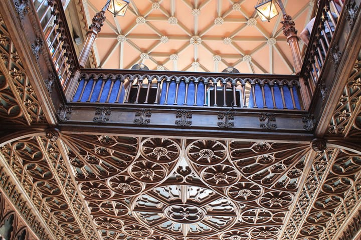 The ornate carved-wood gallery and vaulted ceiling of the historic Livraria Lello bookshop in Porto, Portugal, with bookshelves lining the upper level