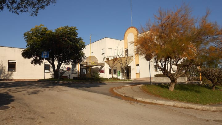 The entrance and car park of the Centro de Saude in Soure, a low cream-coloured Portuguese health centre building