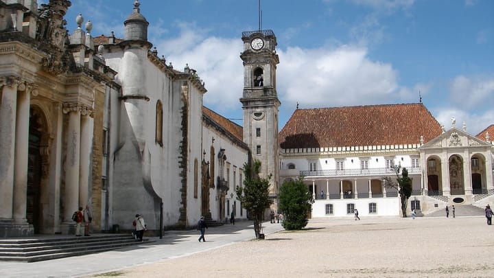 The main courtyard of the University of Coimbra, with its clock tower and a few students crossing the square