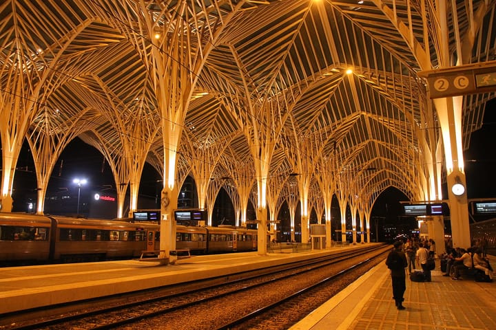 The platform at Gare do Oriente in Lisbon at night, with a CP train beneath the station's steel canopy
